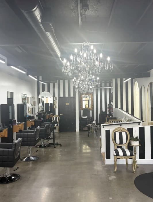The main floor of La Jolie Hair Studio, striped walls under a crystal chandelier